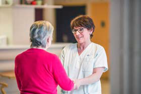 Photo d'une infirmière discutant avec une personne âgée en lui tenant les mains