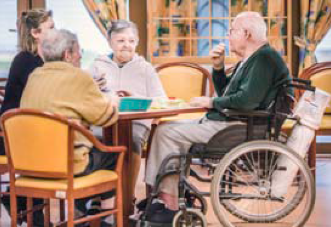 Photo d'un groupe de personnes âgées autour d'une table dans un établissement hébergeant des personnes âgées dépendantes